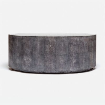 A round, oval coffee table with a grey, faux shagreen top and an antiqued mirror base.