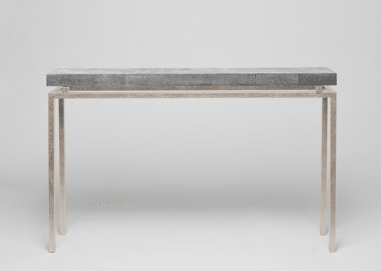 Small modern console table featuring a sleek design with clean lines The table is adorned with a metallic finish and features a