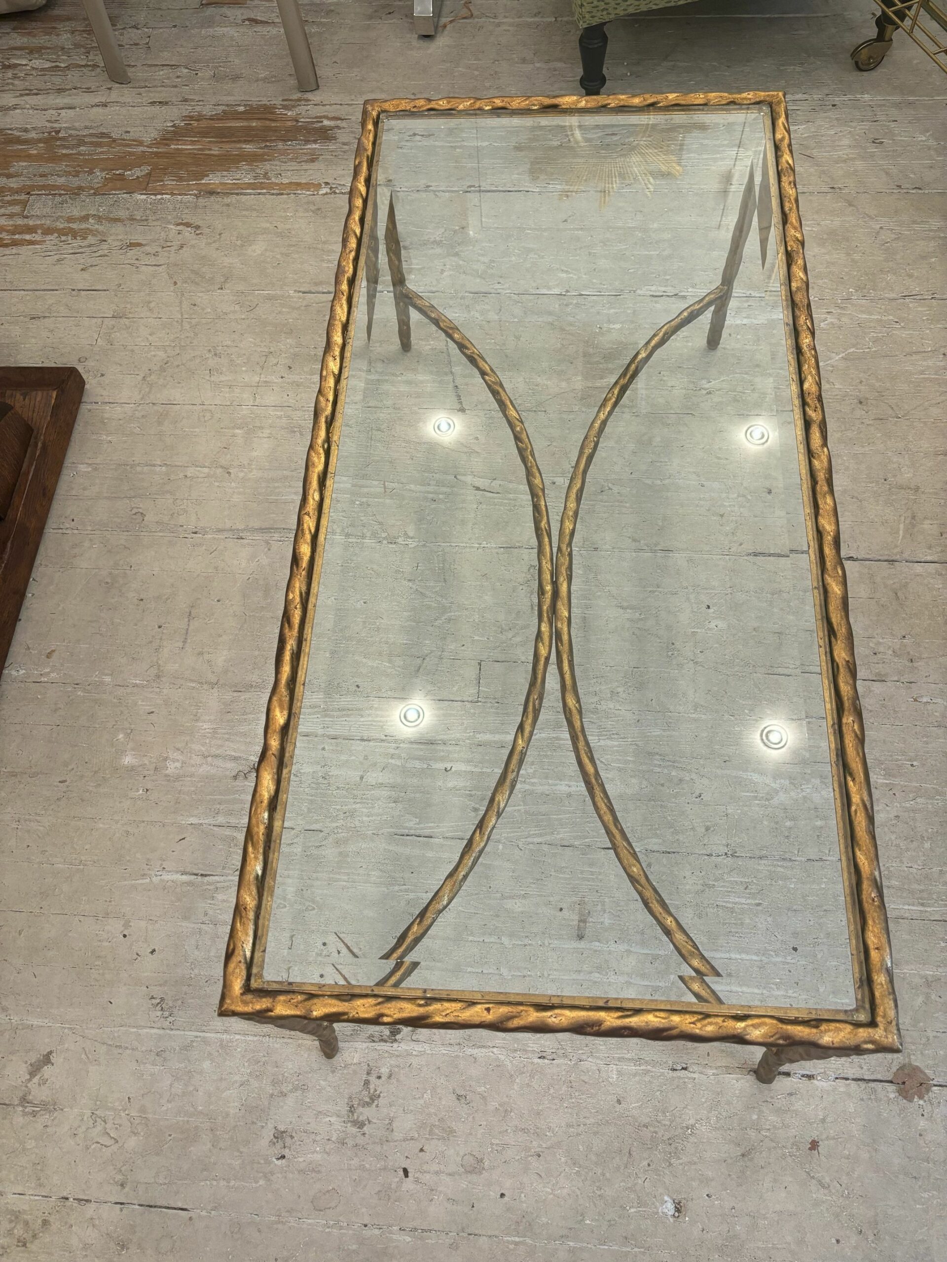 Front view of gilded coffee table featuring twisted metal frame and glass top.