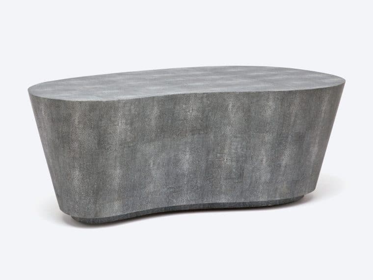A sleek, kidney-shaped coffee table in a mid-century modern style, available in both sand and grey faux shagreen finishes.