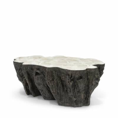 A unique stonecast coffee table shaped like a clam shell with an inlaid fossilized clam shell on a base that resembles a