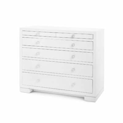 A white lacquered grasscloth dresser with six drawers and chrome handles.