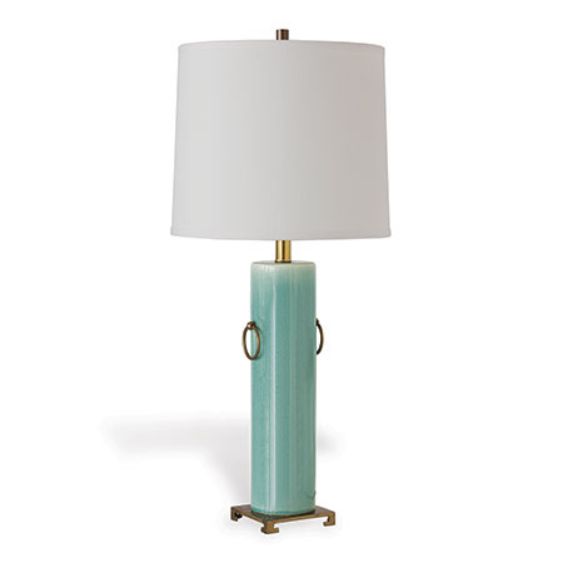 Blue ceramic lamp with brass rings and a white shade on an off-white base, set against a plain background.