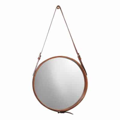 Large round mirror with leather strap and brass knob hanging from top center.