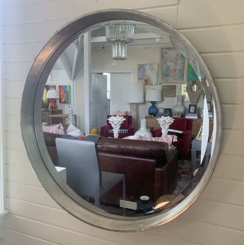 The image features a stylish round mirror which is centrally positioned in a room with various decorative elements The mirror s frame