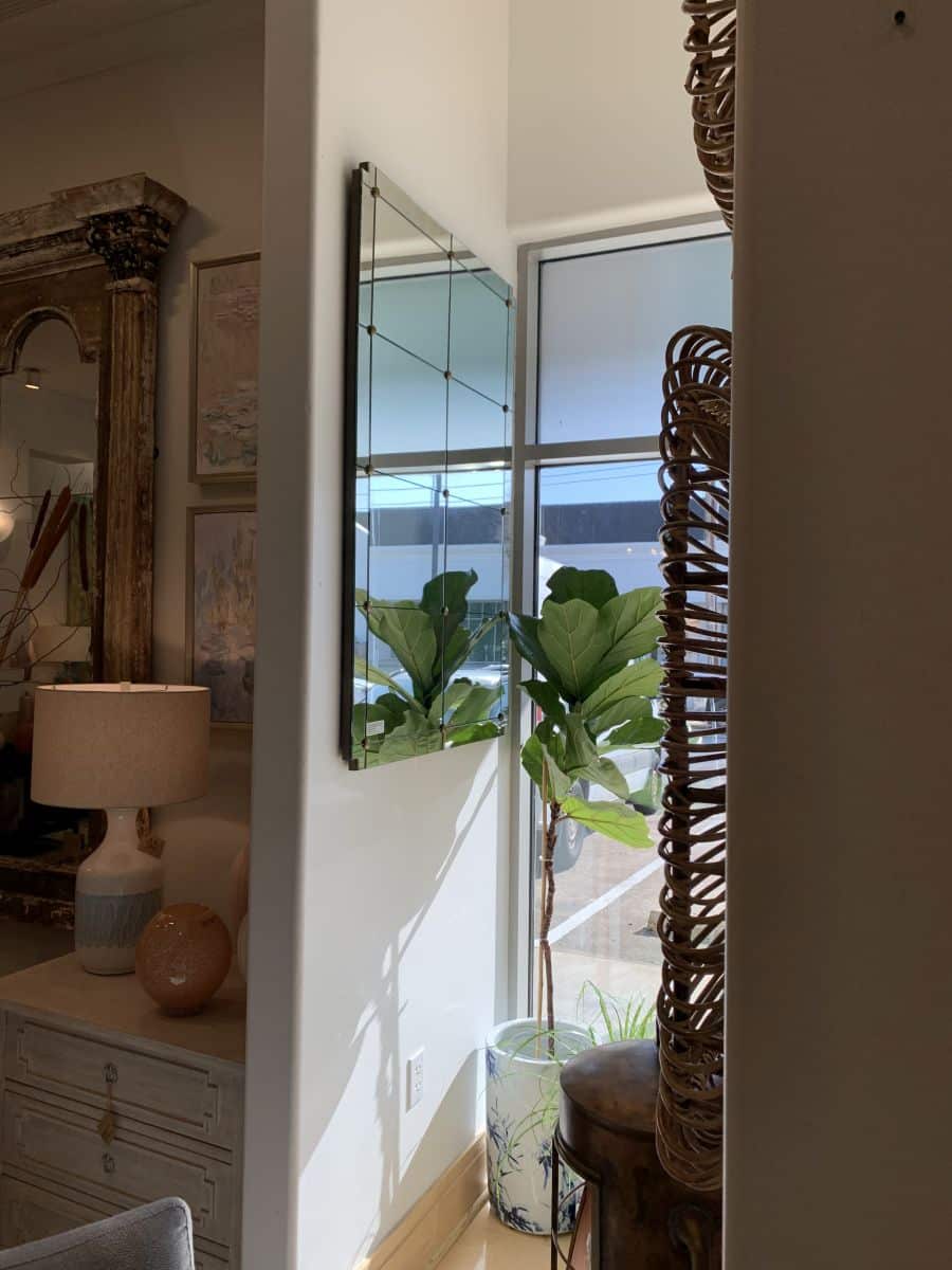 Terese Paneled Mirror, featuring gold details and clipped corners, displayed in a room with a large window.