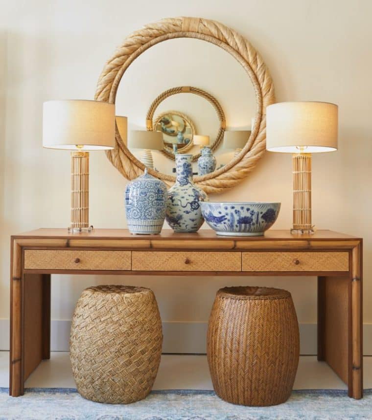 Bamboo table lamp with gold accents and a linen shade displayed on a white table against a beige wallpaper background in front