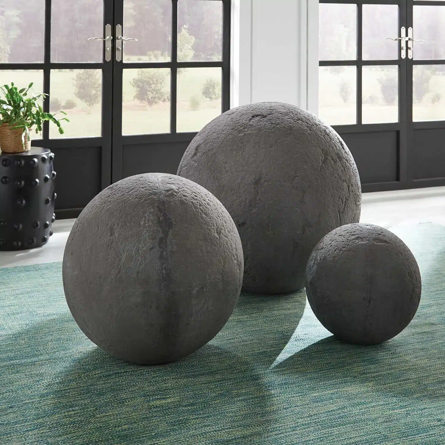 Three large spherical garden ornaments in dark gray concrete available in both distressed light beige and rough dark gray options displayed on