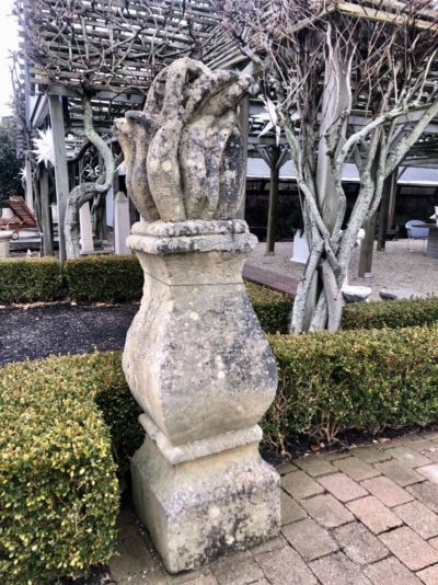 Large ornate stone decoration against a backdrop of trees and greenery.