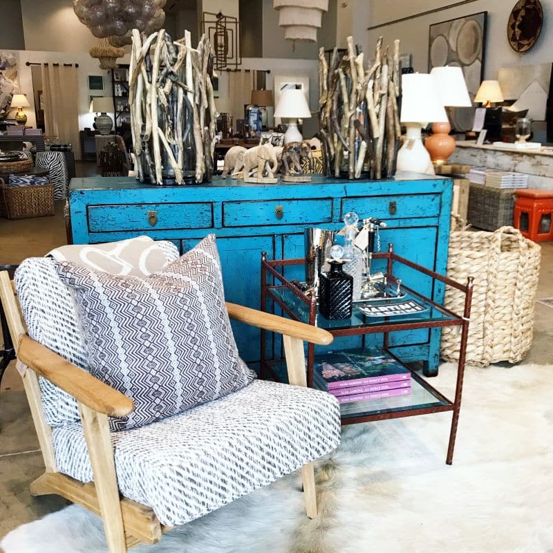 Leather wrapped side table with glass shelves and brass finials, placed in a store display.