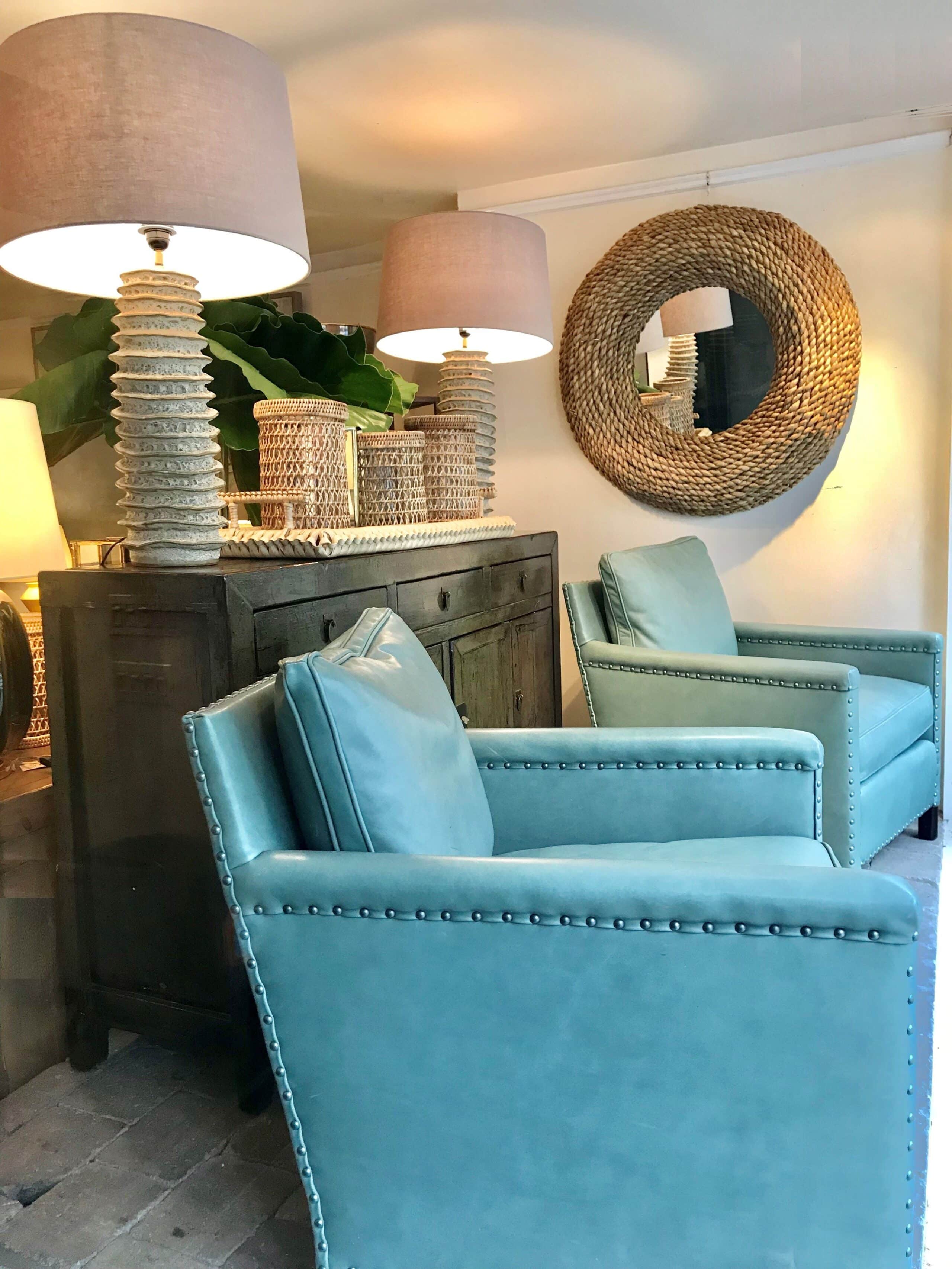 A blue leather armchair in a room with a wicker wall decoration and a lamp.