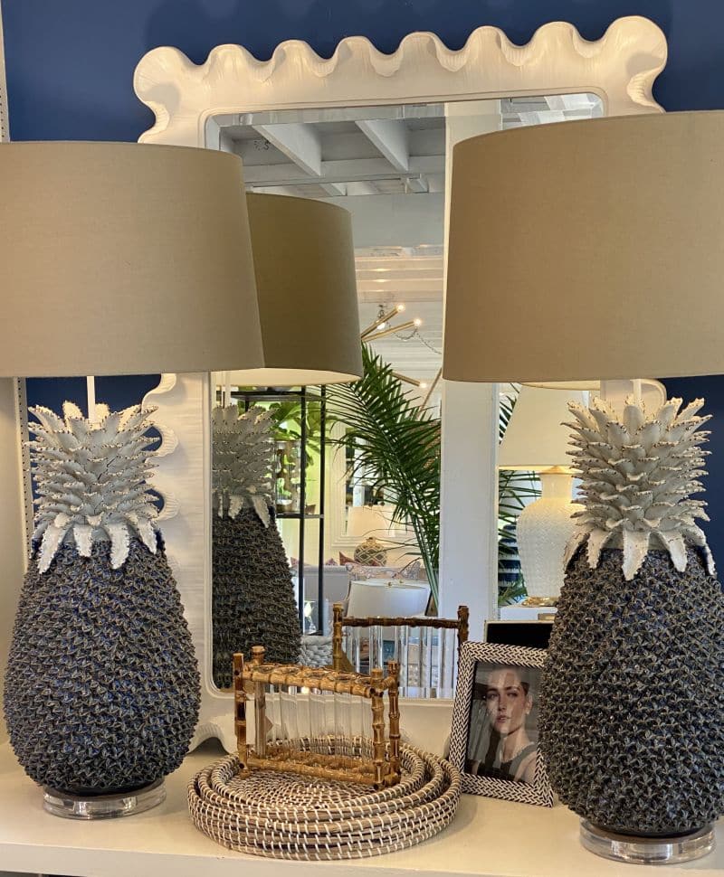 Large white resin wave mirror on display, set against a wall decorated with pineapple-shaped decorations.