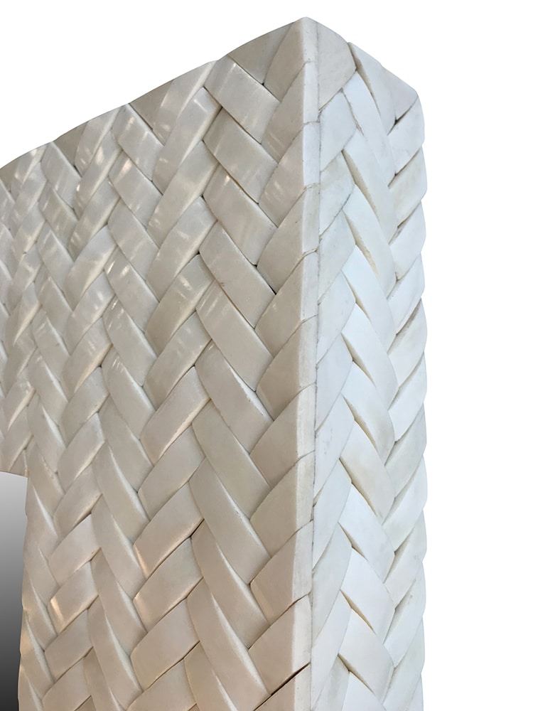 A white woven basket with a bone frame, showcasing intricate weaving patterns.
