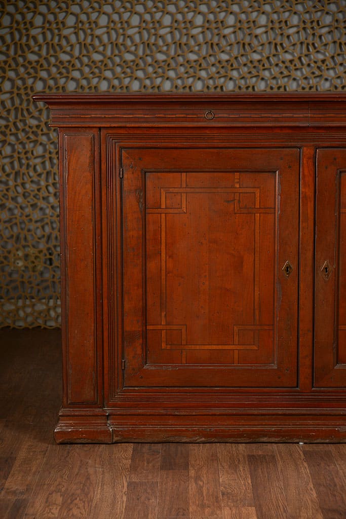 Wooden buffet with two doors and two drawers, featuring inlaid wood design on a dark background.