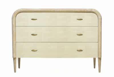 A light brown wooden dresser with a curved frame and tapered legs, featuring three drawers and brass handles.