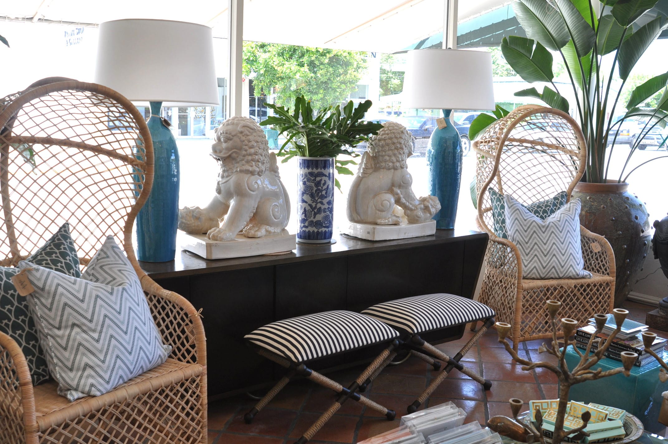Black and white striped X rope stool with a rustic iron frame, placed in front of a window with plants.