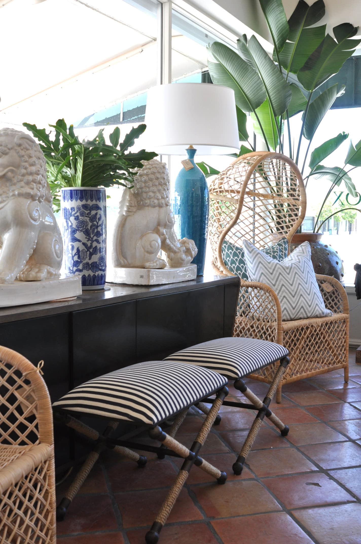 A striped X rope stool with a rustic iron frame placed on a tiled floor in front of a window next to