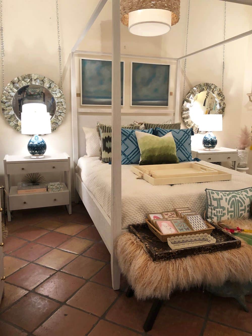A large bedroom with a white four poster bed and a white shagreen nightstand on one side.