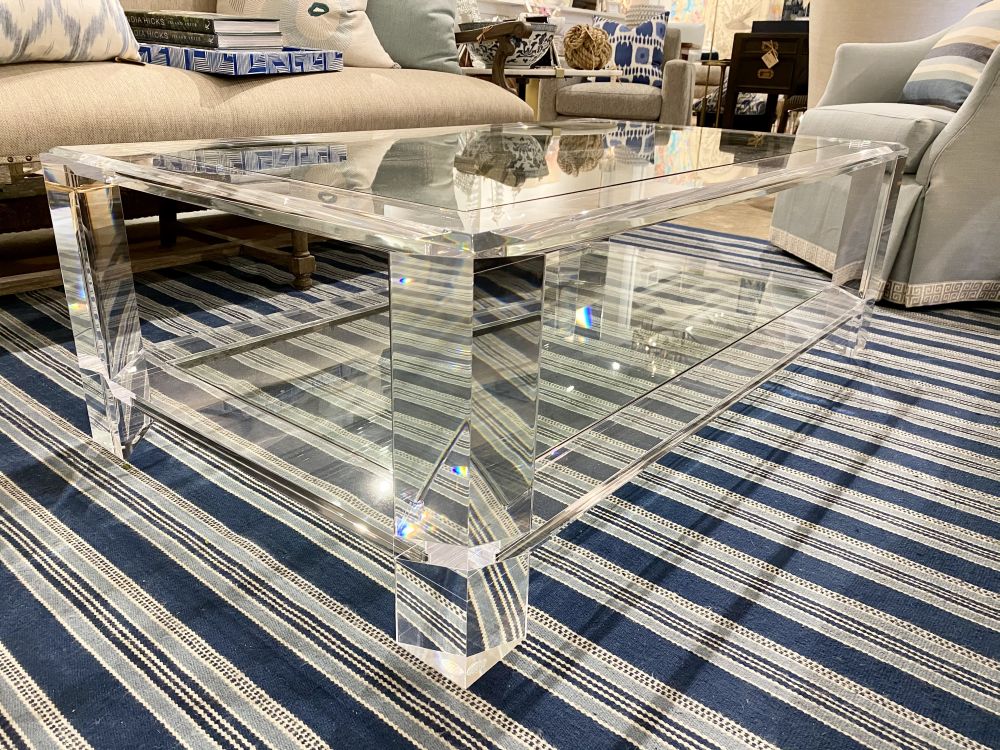 A glass and acrylic coffee table with a bottom glass shelf, showcasing its sleek design and transparency.