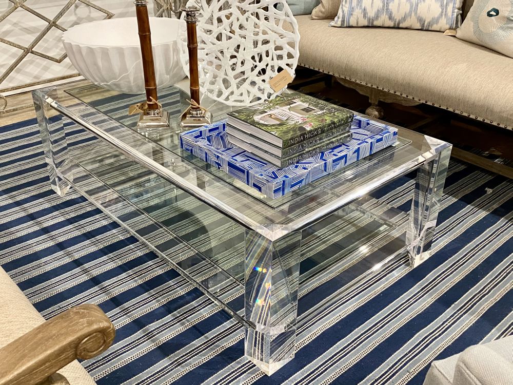 Clear glass coffee table with acrylic top and bottom shelf, showcasing a modern design on a blue patterned carpet.