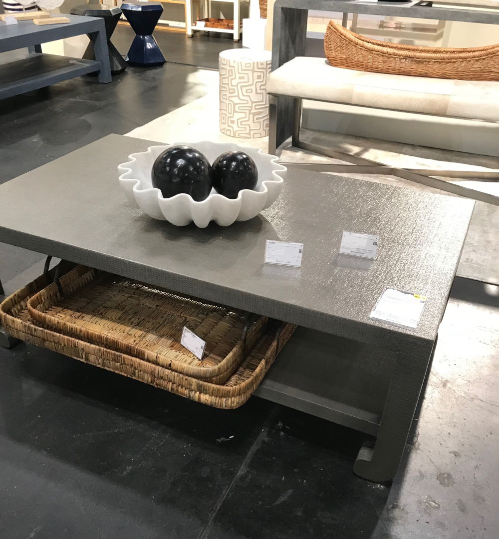 Ming style faux raffia coffee table on display in a furniture store available in French gray and pristine or seal French gray
