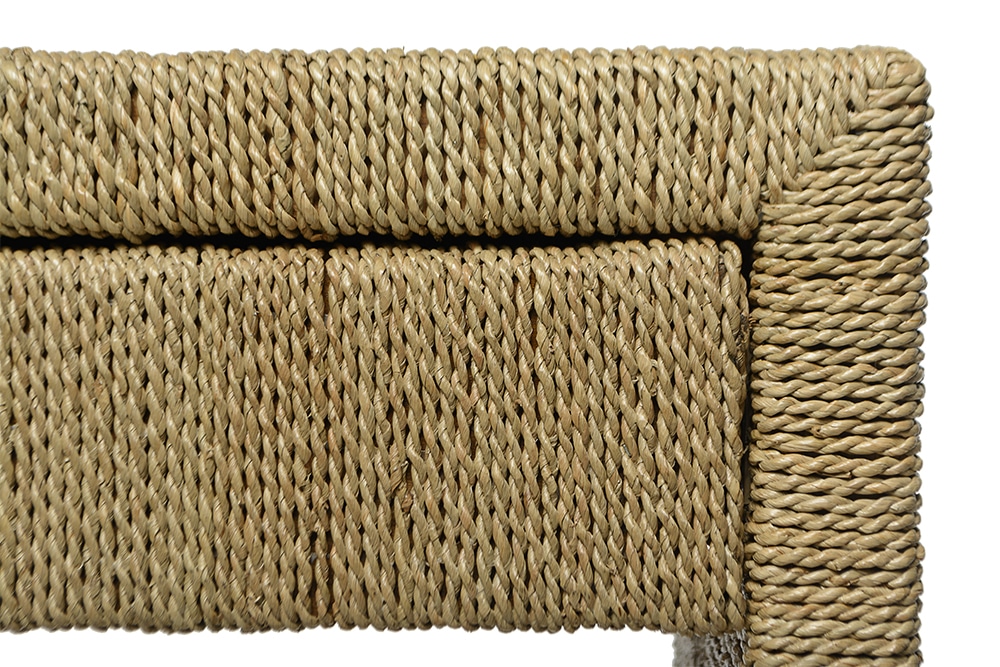 Wicker side table with a rope texture, featuring a drawer and two shelves, against a white background.