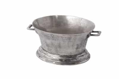 A silver metal wine cooler with a wide rim, placed on a white surface.