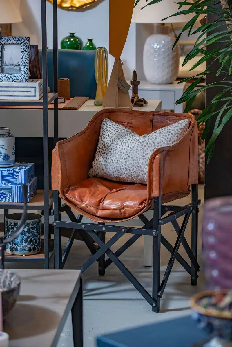 Leather Paris Cafe chair in a shop featuring a teak frame stained dark and a loose cushion hand tanned showcasing its unique