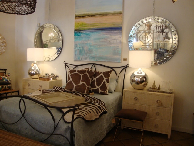 Large round antiqued aged Venetian bubble frame mirror in a bedroom setting, with two smaller mirrors in the background on either side.
