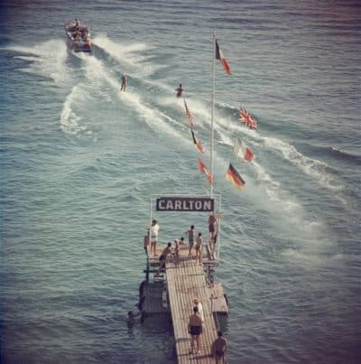 Cannes Watersports Reproduction Photograph A black and white image showcasing a vintage scene at a dock with a boat people and flags