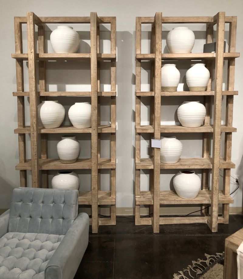 Wooden bookcase with three shelves, each holding a white vase.