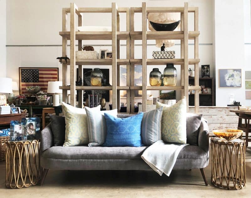 Hans Reclaimed Wood Bookcase in Light White Wash with Decorative Bowls and Blue Throw Pillows on a Grey Couch