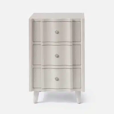A small, light beige nightstand with three drawers and a knob on each drawer.