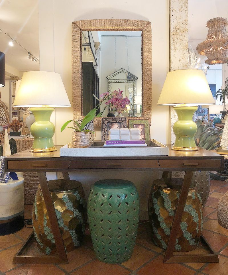 A squared edged rope mirror with darker rope framing at angled corners placed on a table in a room with a lamp