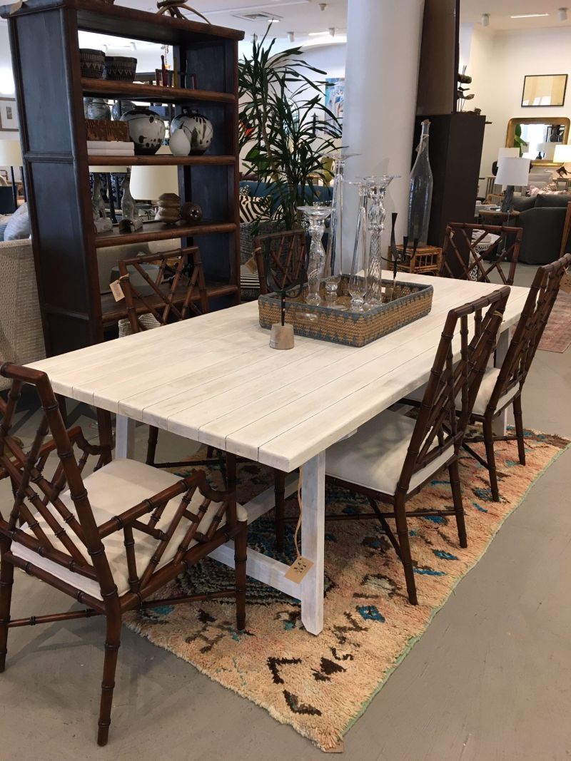 A large, rustic wooden dining table with a white top and brown legs in a modern room.