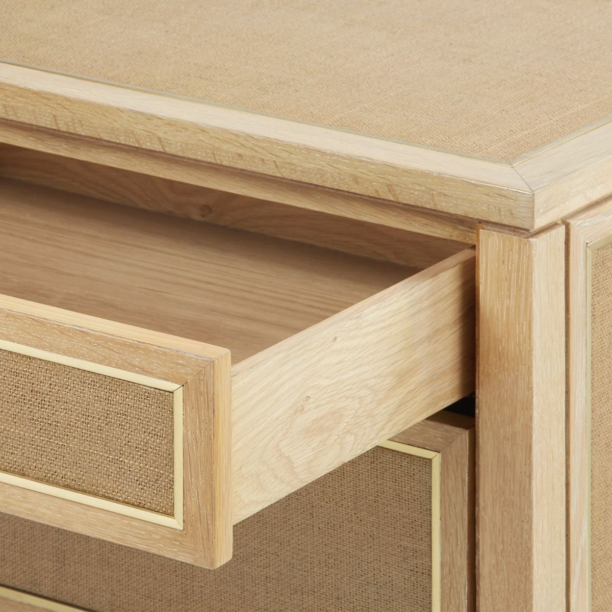 Three drawer nightstand with natural oak finish and woven jute panels, featuring solid brass pulls