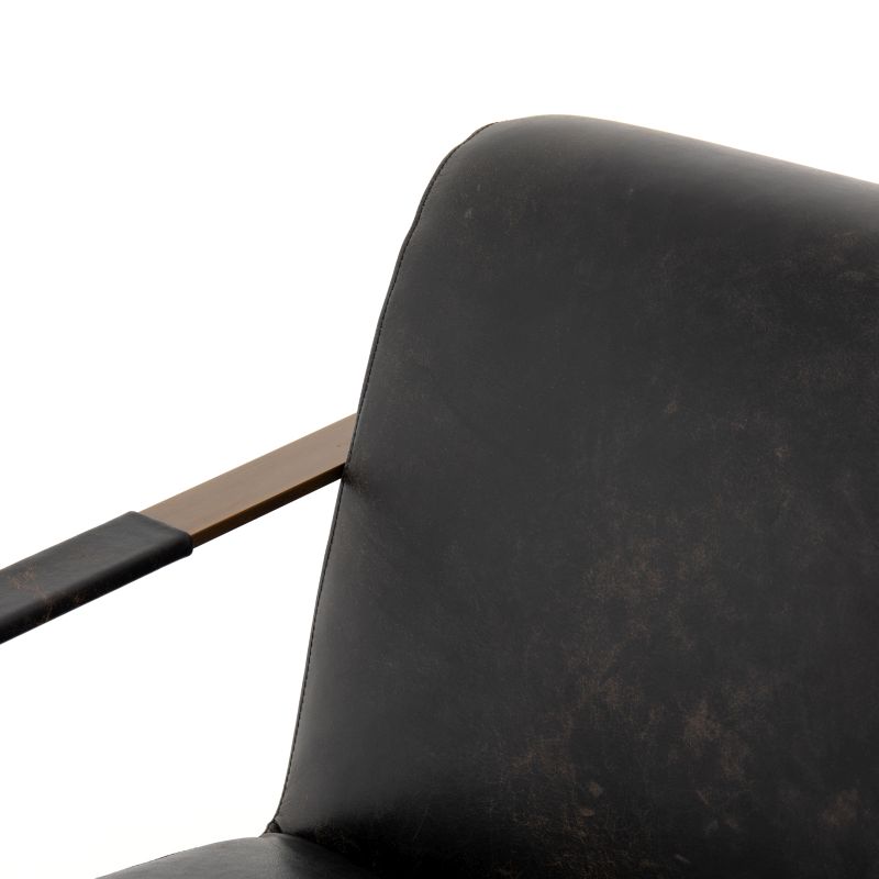 Black leather armchair with brass frame, showcasing a luxurious and comfortable seating option for a bedroom or living room.