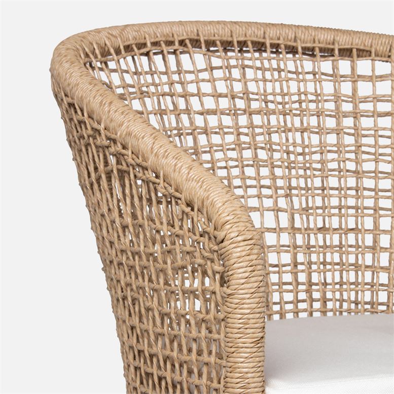 Wicker outdoor armchair with a curved frame, white fabric upholstery, and a natural twisting design.