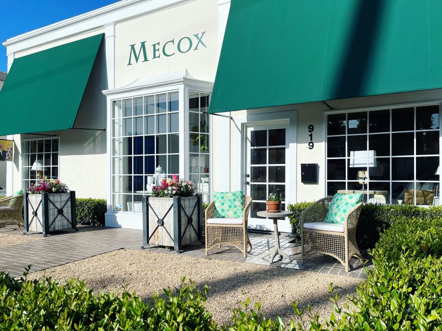 A white building with a green awning outdoor seating area featuring a natural twisted faux wicker arm chair with a curved frame