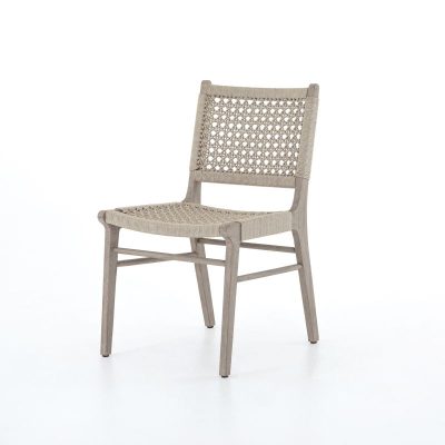 An outdoor dining chair with a woven ivory rope seat and back constructed from weathered teak wood showcasing a blend of natural