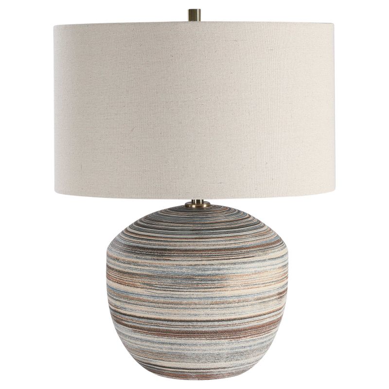 Brown and blue striped table lamp with a linen drum shade featuring natural slubbing and brass hardware on display against a white