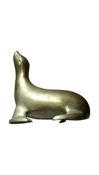 This image displays a large vintage brass figure of a sea lion characterized by its head raised in the air The sea