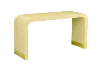 A modern, cream raffia console with an antiqued brass base and a glass top, against a white background.