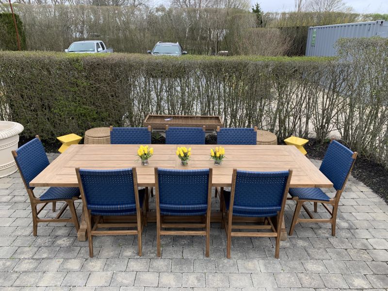 The image displays an outdoor dining area featuring a set of six blue Hammond side chairs with natural teak accents arranged around