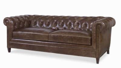 Dark brown leather Chesterfield sofa with spring down seat cushions and dark brass nail trim presented in a showroom setting against a