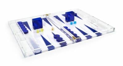 A clear acrylic backgammon game set with blue and white pieces on a table, also available in orange.