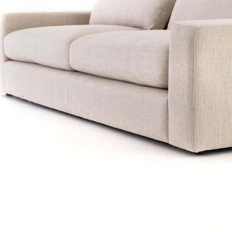 A beige sofa with a plush cushioned seat and back featuring a combination of foam and fiber padding displayed in a clean