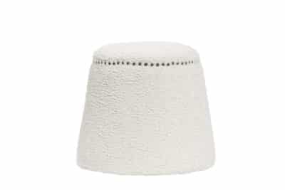 A round, white ottoman with a textured fabric surface and black nail head trim around its base.