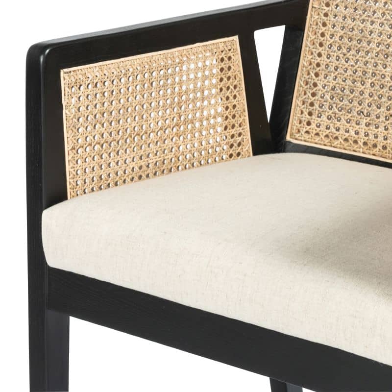 A close-up of a black and beige wicker bar stool with a cushioned seat.