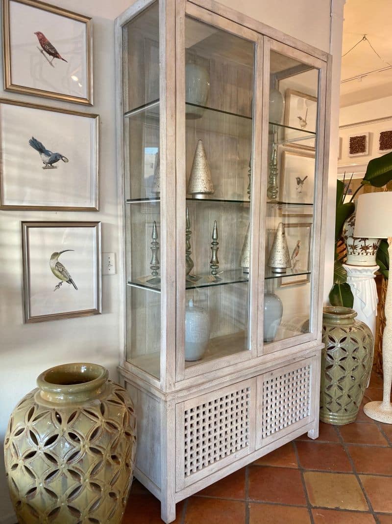 Tall lattice white washed driftwood cabinet with glass shelves and doors.